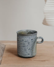 Load image into Gallery viewer, Speckled gray wood fired mug on a wooden surface with a neutral background
